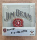 A sealed retail box for a set of four Jim Beam glass coasters, photographed from above on a tan surface. The box is mostly white and clear, with large stylized Jim Beam lettering, a red wax-seal style logo, and vertical text reading 'SET OF 4 GLASS COASTERS' and 'MAKE HISTORY Jim Beam.